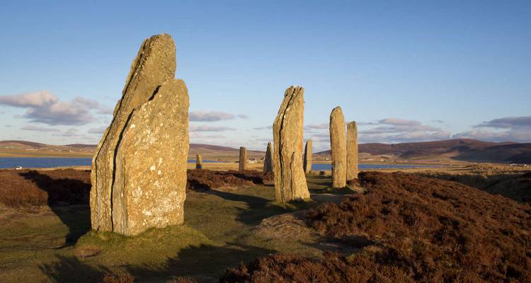 Ancient stone circle in a grassland setting with a blue sky.