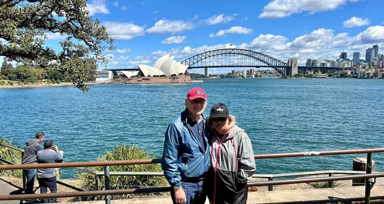 Couple posant près d'une balustrade avec un pont et un opéra en arrière-plan.