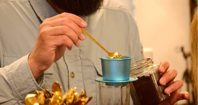 Primer plano de una mano sacando café molido de un frasco.