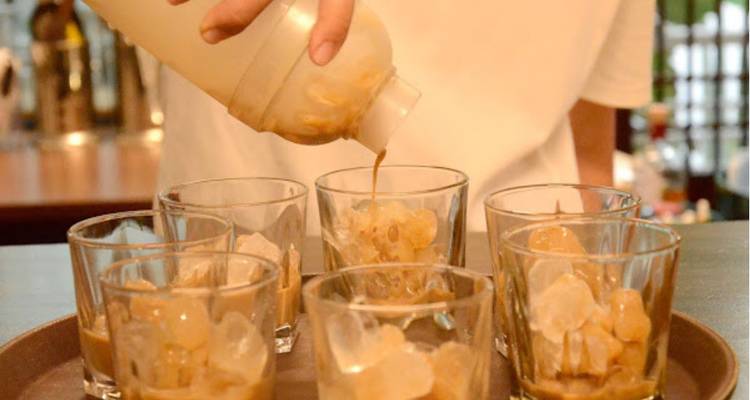 Persona vertiendo café en vasos con hielo.