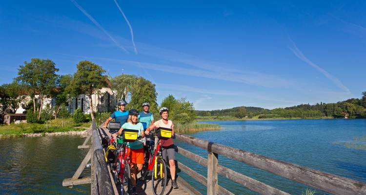 Grupo de ciclistas caminando con bicicletas a través de un puente de madera pintoresco.