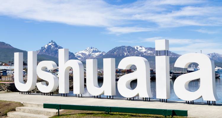 Grand panneau d'Ushuaia avec des montagnes en arrière-plan.