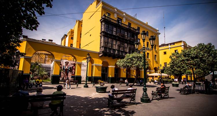 Colorful buildings in a city with people walking in the foreground.
