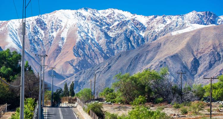 Route de montagne avec des sommets enneigés en arrière-plan.