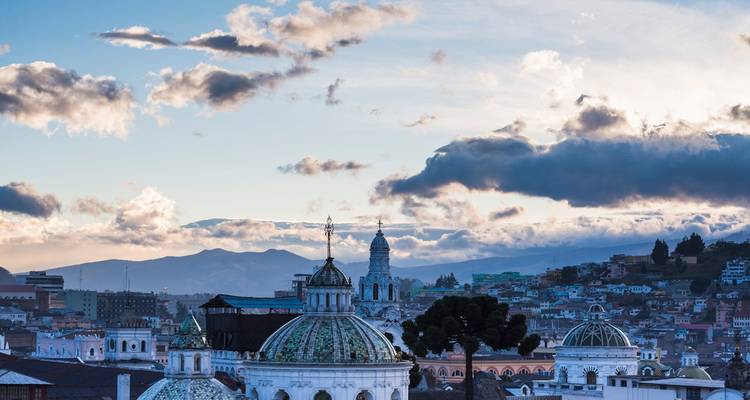 Blick vom Dach auf eine Stadt mit Bergkulisse im Hintergrund.