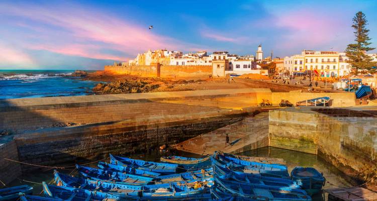 Barcos azules coloridos atracados en un vibrante pueblo portuario con cielo brillante en Essaouira, Marruecos.