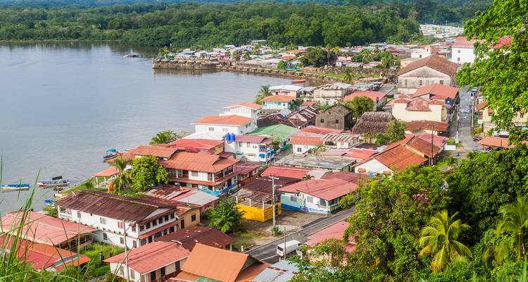 Pueblo tropical junto al río con techos coloridos rodeado de exuberante vegetación