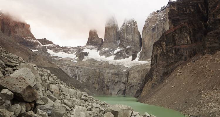 Paysage rocheux avec des pics enneigés et un lac turquoise.