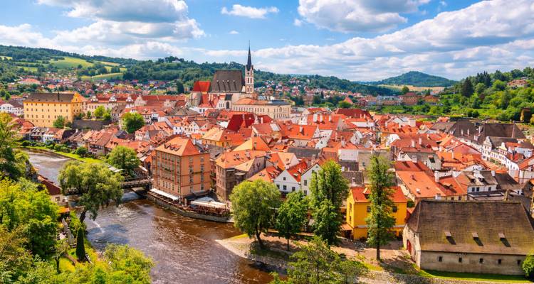Ville colorée de Cesky Krumlov avec une rivière et des collines vertes.