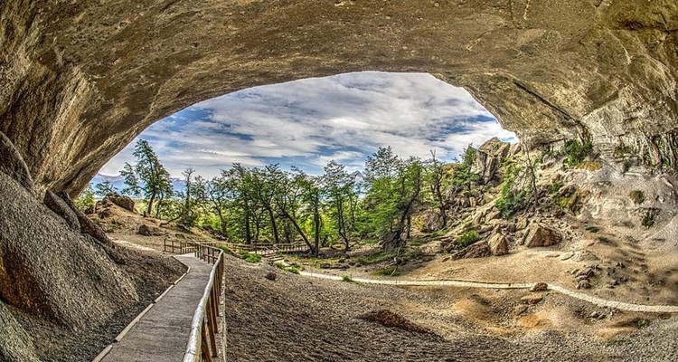 Breed stenen pad leidt door de spectaculaire boog van Milodonhöhle naar het weelderige bos erbuiten