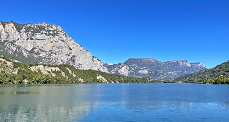 Lac alpin aux eaux cristallines reflétant les pics calcaires escarpés sous un ciel sans nuages.