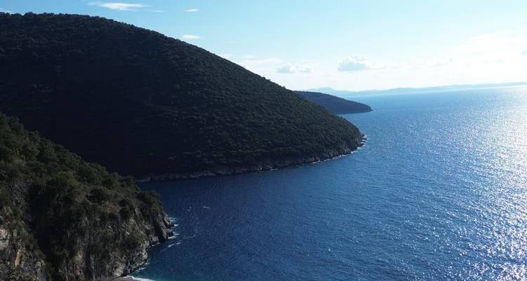 Hermosa costa con una colina empinada y boscosa y mar azul.