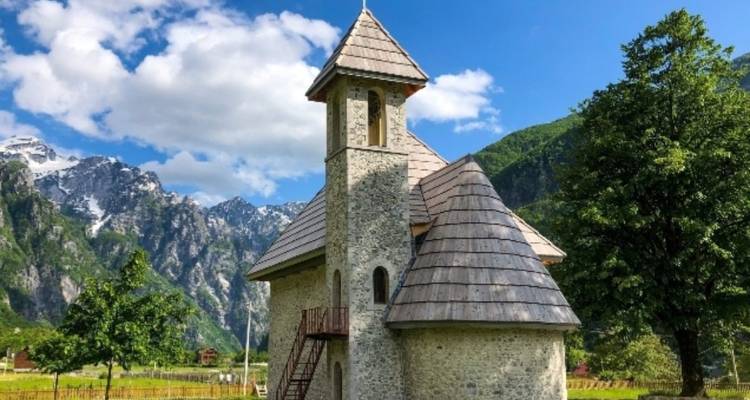 Iglesia de piedra rodeada de exuberante vegetación y montañas.