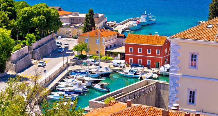 Un quai avec des bateaux dans une ville côtière animée entourée de bâtiments colorés.