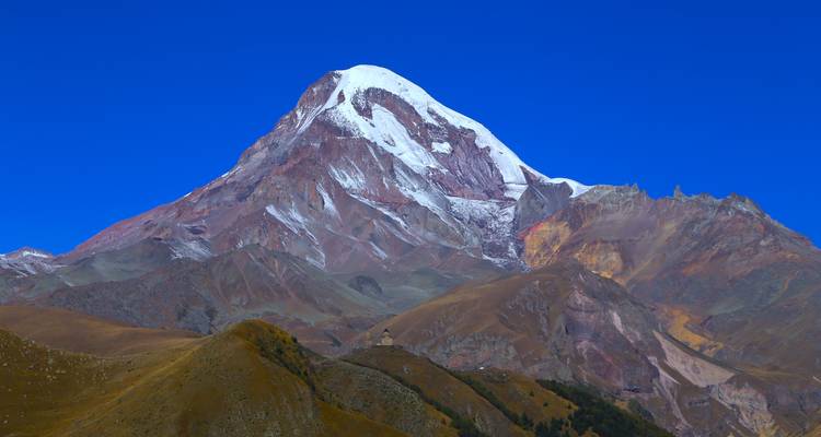 Majestuosa montaña cubierta de nieve bajo un cielo azul despejado.