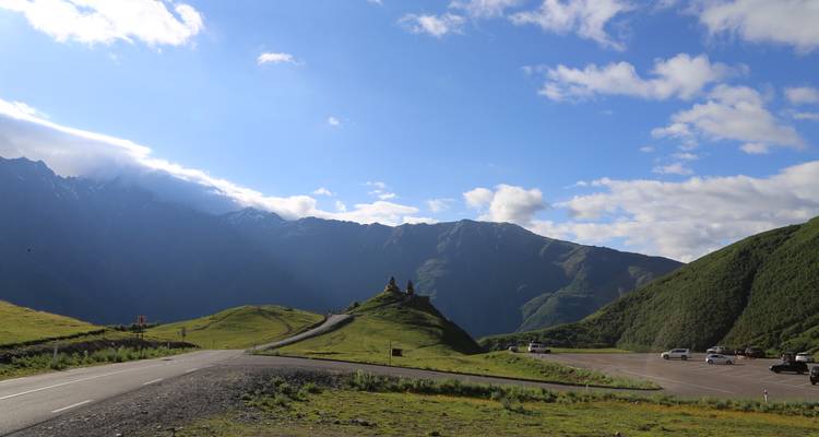 Una meseta con una hermosa vista de las montañas y una pequeña capilla.