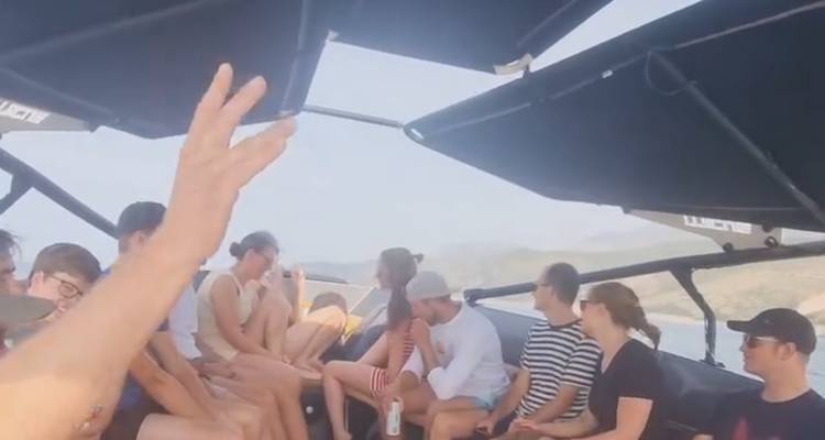 Personas sentadas en un bote con toldo negro, conversando.