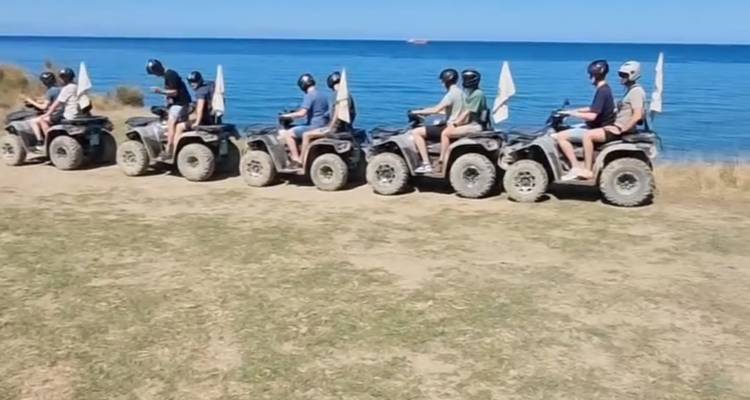 Personas montando vehículos todo terreno por un sendero costero pintoresco.