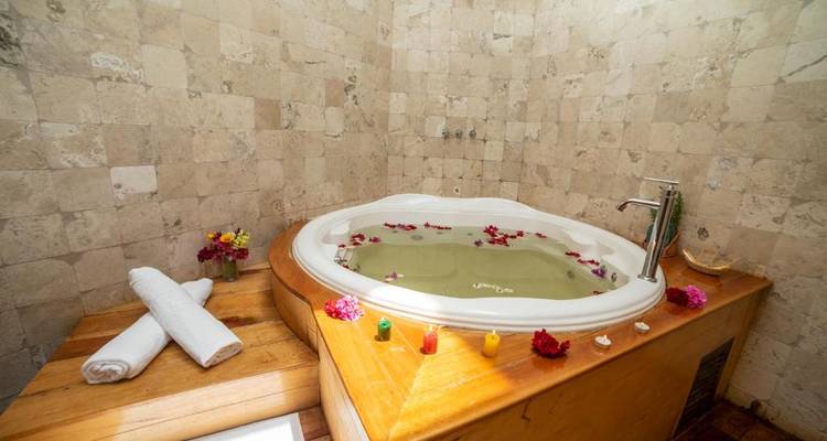 Un jacuzzi avec des pétales de fleurs à la surface de l'eau dans une pièce chaleureuse.