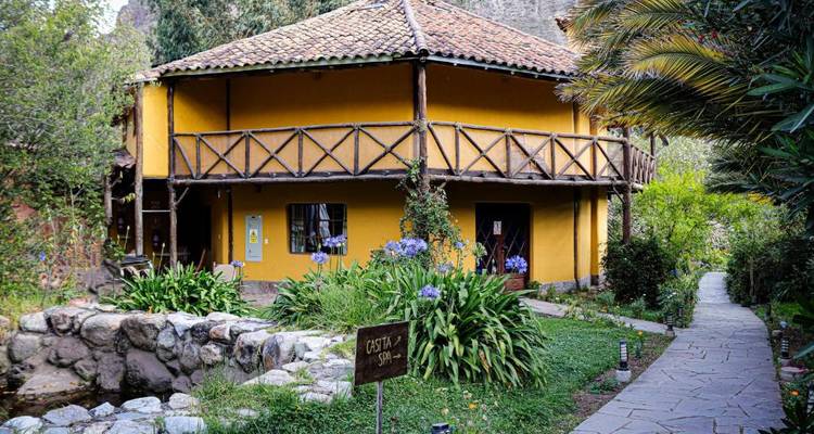 Extérieur d'un lodge rustique entouré de verdure et de fleurs.