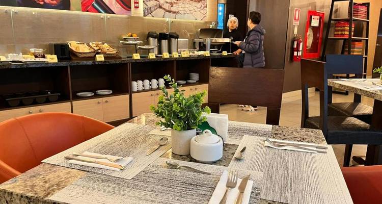 Zone buffet avec une variété d'articles de petit-déjeuner et deux personnes servant la nourriture.