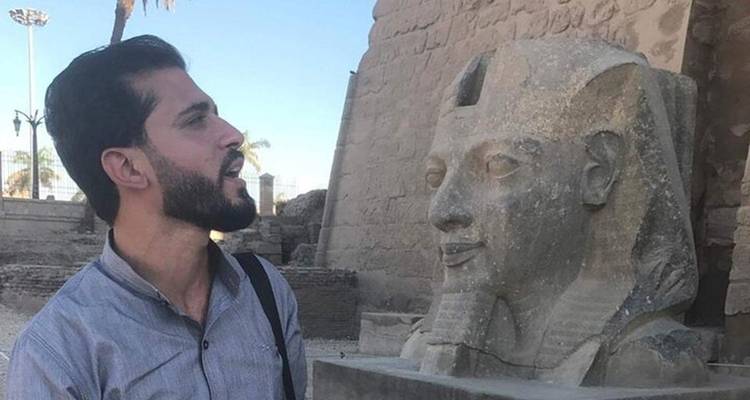 Hombre mirando una estatua antigua.