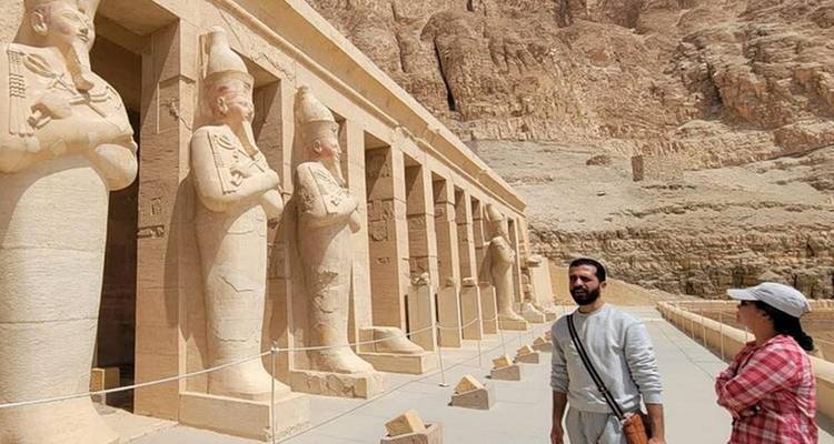 Dos turistas explorando estatuas en Luxor.