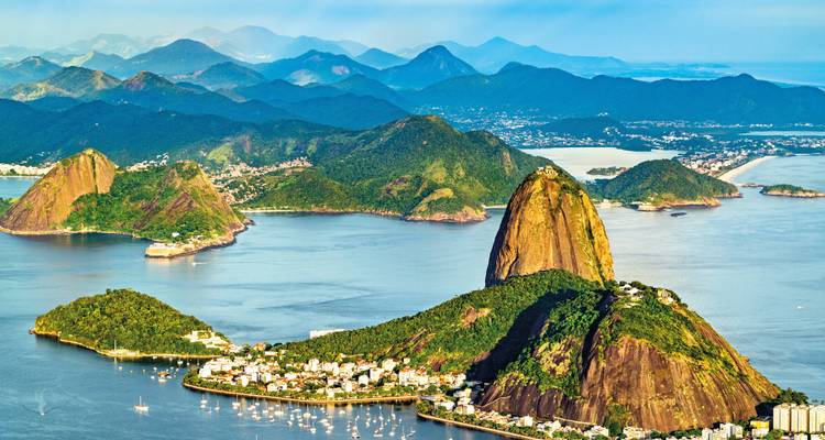 Vista aérea de la Montaña del Pan de Azúcar y la Bahía de Guanabara con montañas azules superpuestas en la distancia