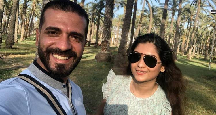 Una pareja posando entre palmeras en un ambiente soleado.