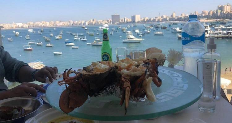 Un ambiente de comedor con mariscos y vista a un puerto concurrido.