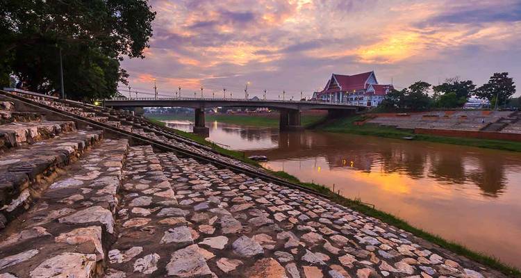 River scene with bridge and traditional building at dusk.