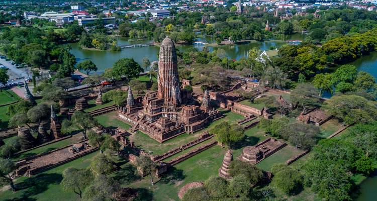 Drone view of an ancient Ayutthaya temple complex surrounded by moats and leafy parks.