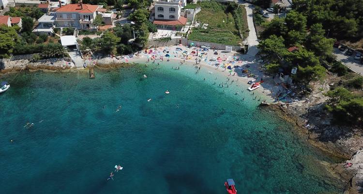 Pequeña playa con gente relajándose junto al mar turquesa.