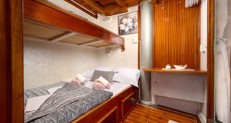 Interior de una cabaña acogedora con una cama doble en un barco.