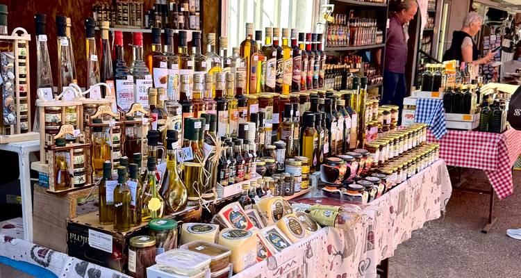 Puesto de mercado que exhibe una variedad de productos locales y botellas.