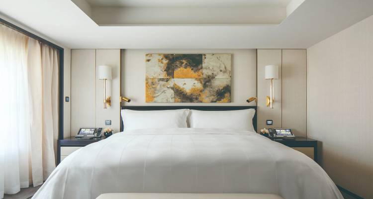 Bright, contemporary hotel bedroom with plush white bedding and neutral tones.
