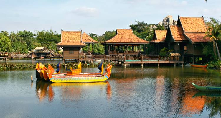Pavillons traditionnels en bois et un bateau-dragon aux couleurs éclatantes sur un lac tranquille.