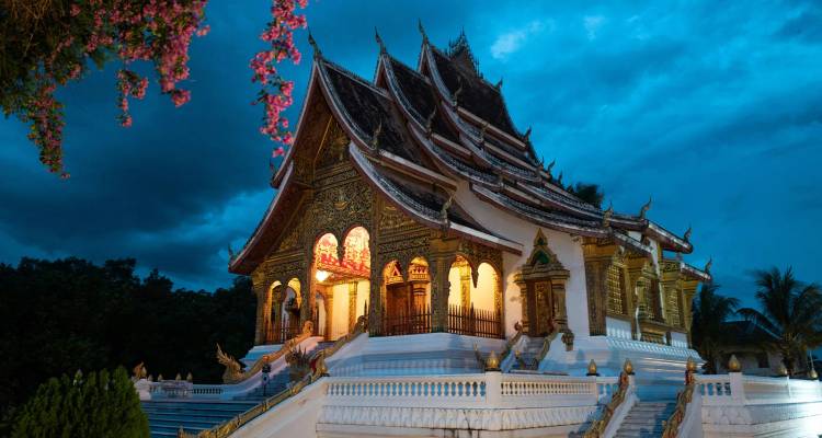 Temple illuminé aux toits étagés ornementés qui brille au crépuscule sous un ciel du soir bleu dramatique.