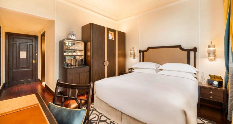 Acogedora habitación de hotel boutique con tonos cálidos, piso de madera y minibar equipado.
