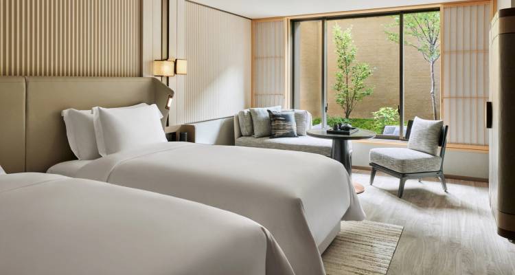 Elegante habitación de hotel moderna con dos camas individuales y zona de estar con vista a un pequeño jardín