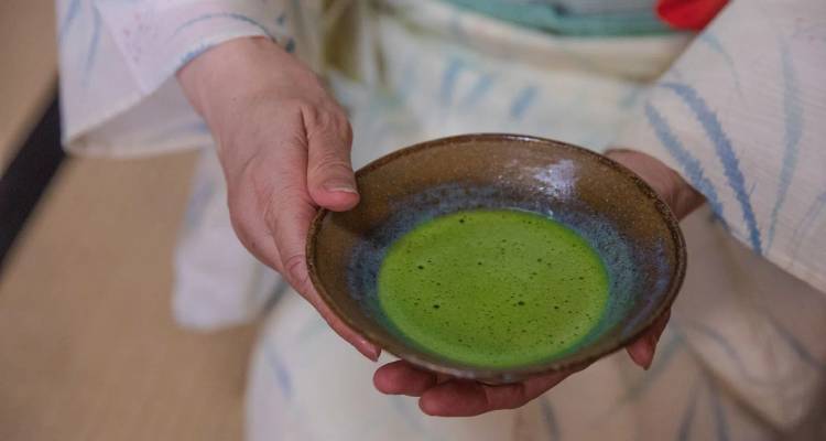 Primer plano de té verde matcha tradicional servido en un bol durante la ceremonia del té