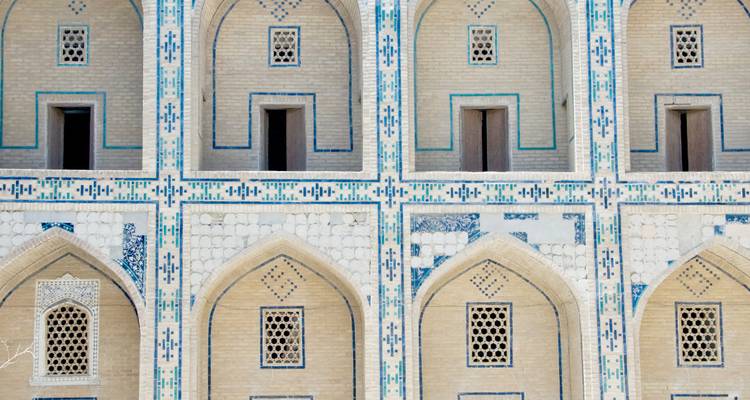 Primer plano de la fachada simétrica con ventanas arqueadas y detalles en azulejos turquesas