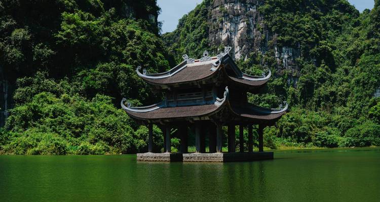 A traditional Vietnamese pagoda on a serene lake with lush greenery.