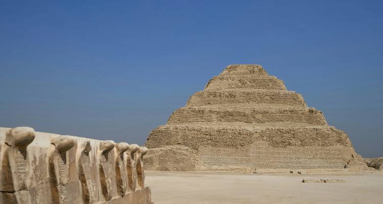 The Step Pyramid of Djoser rises from the desert under a clear blue Egyptian sky.