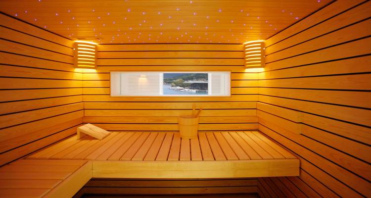 Wooden sauna interior with soft lighting and window view of a lake