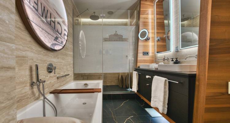 Stylish hotel bathroom with bathtub, glass shower and wooden accents, clean and well-lit.
