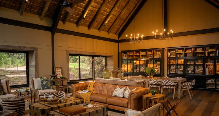 Warm, stylish safari lodge lounge with thatched roof, leather sofas and nature-inspired décor.