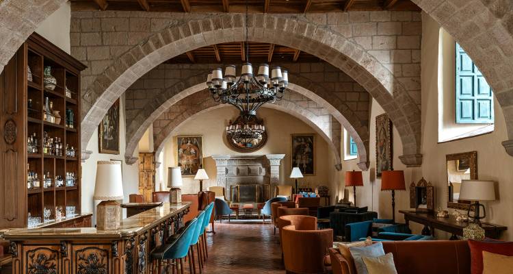 Elegant hotel lounge with stone arches, chandelier and comfortable colourful seating.