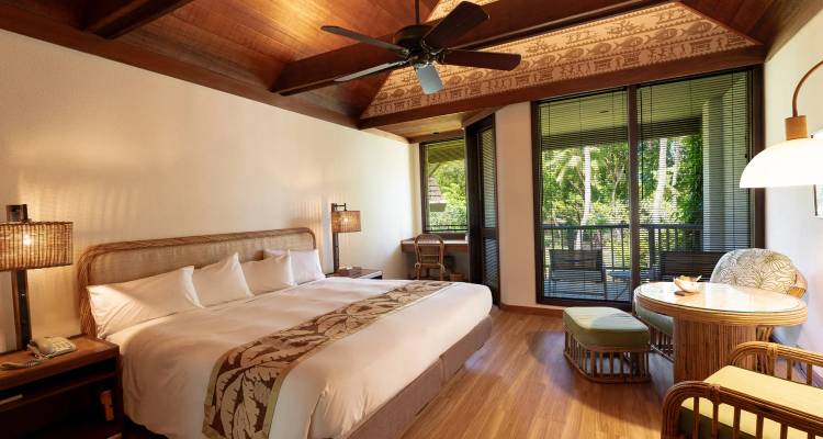 Spacious tropical resort bedroom with king-size bed, wooden ceiling fan and balcony facing lush forest greenery.