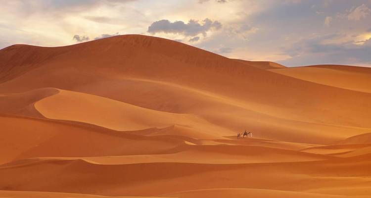 Amplio paisaje desértico con dunas de arena al atardecer.